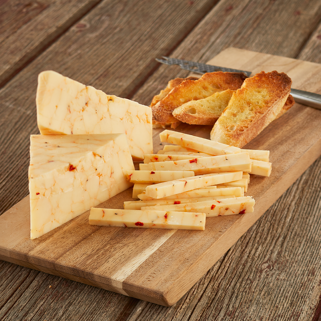 Sliced cheese on wooden cutting board with toasted bread